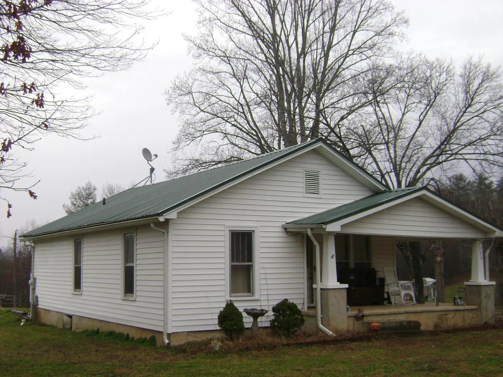 Green metal roof on a white bungalow with a side porch in Cascade